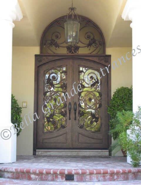 Photo of a beautiful double iron door with an iron grill placed at the top. The door also has a front light and it has been installed at a house in Las Vegas. This stunning creation has been proudly crafted by Bella Grande Entrances.