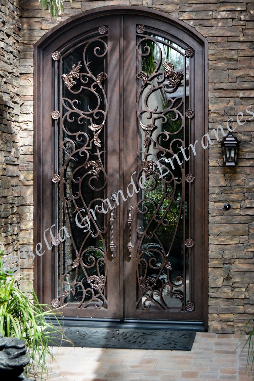 Close-up photo of an elegant double iron door, along with an iron side light, at the entrance of a house in Las Vegas. This beautiful entrance has been skillfully crafted by Bella Grande Entrances.
