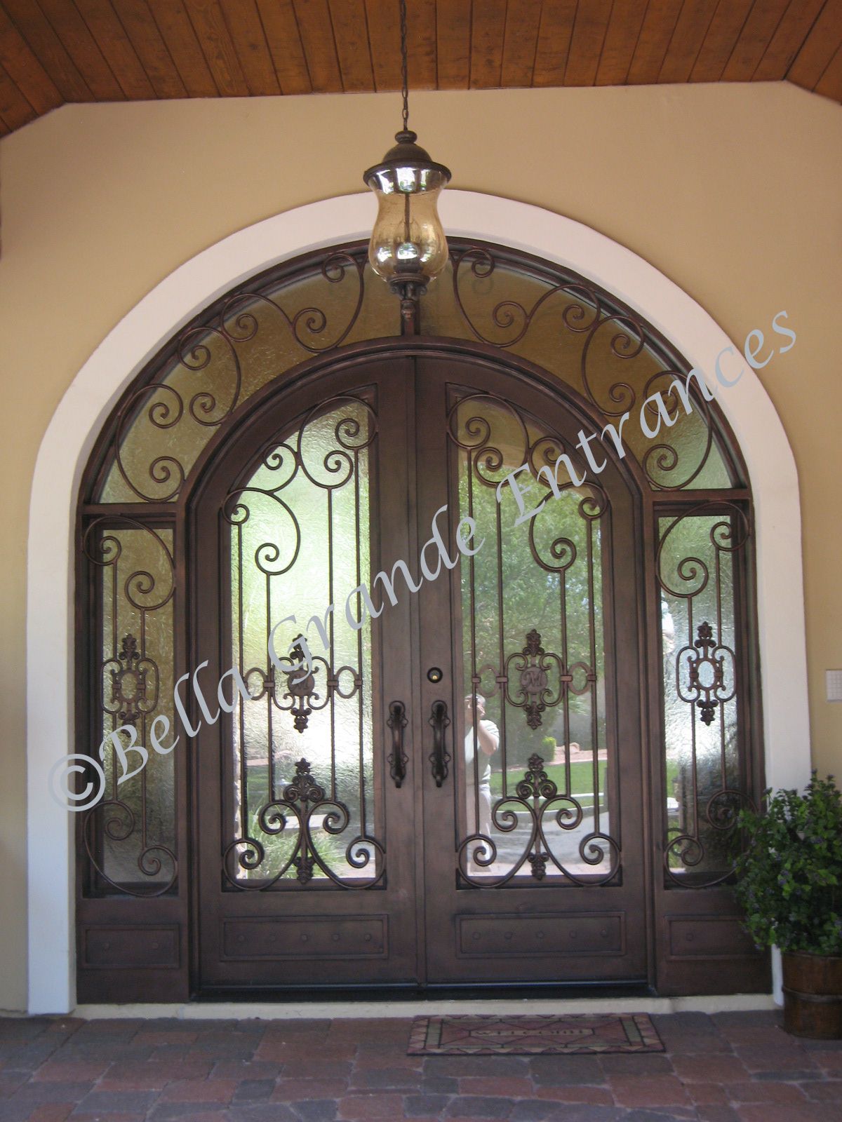 A detailed picture of a house entrance designed by Bella Grande Entrances, showing a double iron door with side lights.